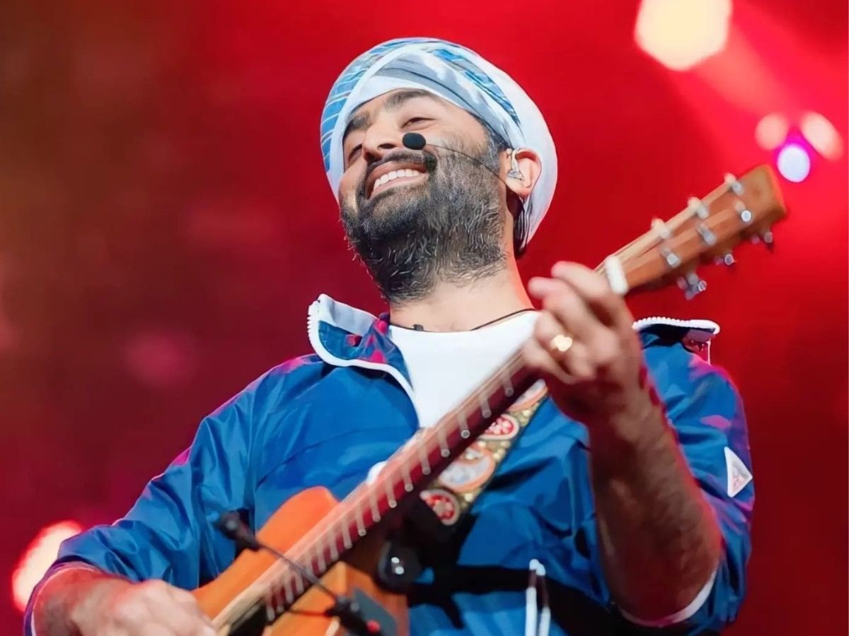 Neon‑lit silhouette of Arijit Singh in Bangalore, guitar raised