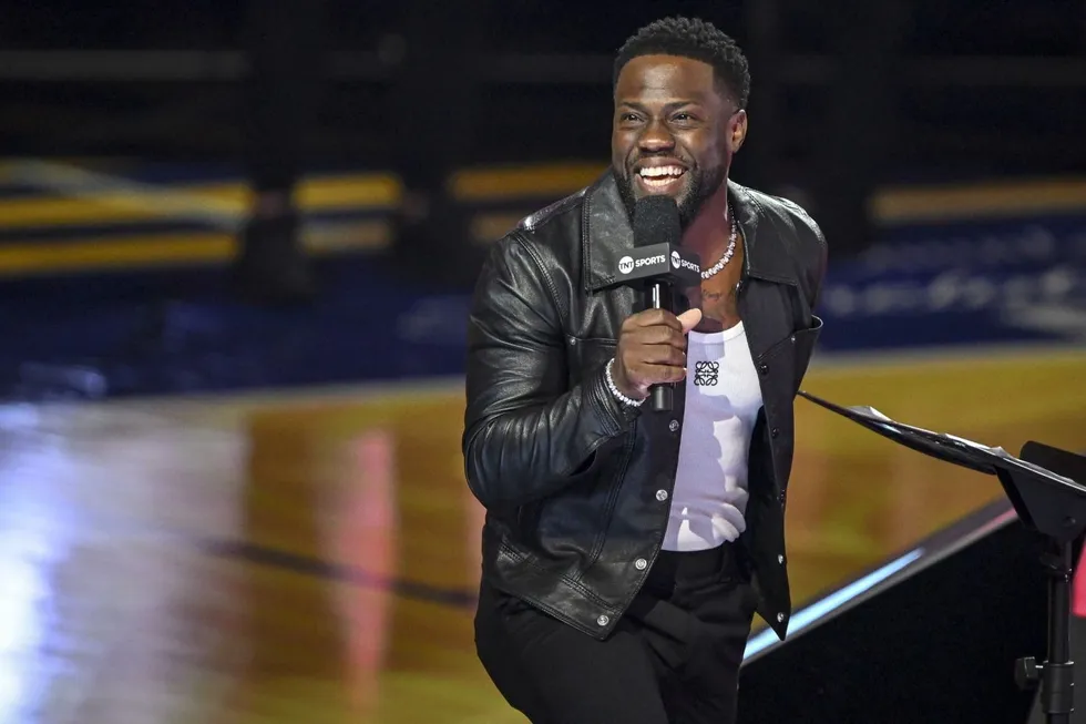 Kevin Hart at a BET press conference, laughing mid-answer with BET and Paramount logos behind him